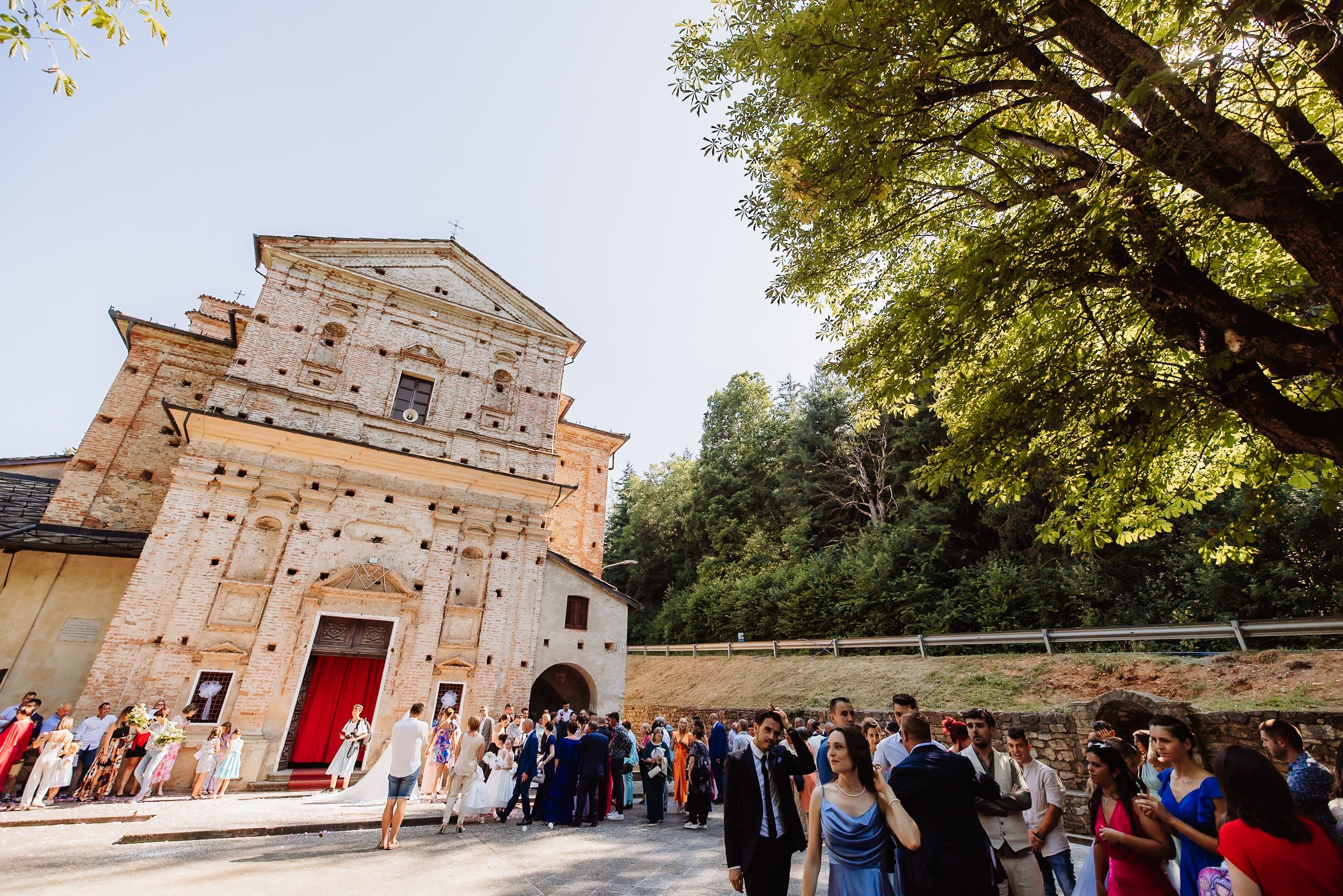 Historic church exterior with large wooden doors and stone facade as crowds of tourists gather on a sunny autumn day.