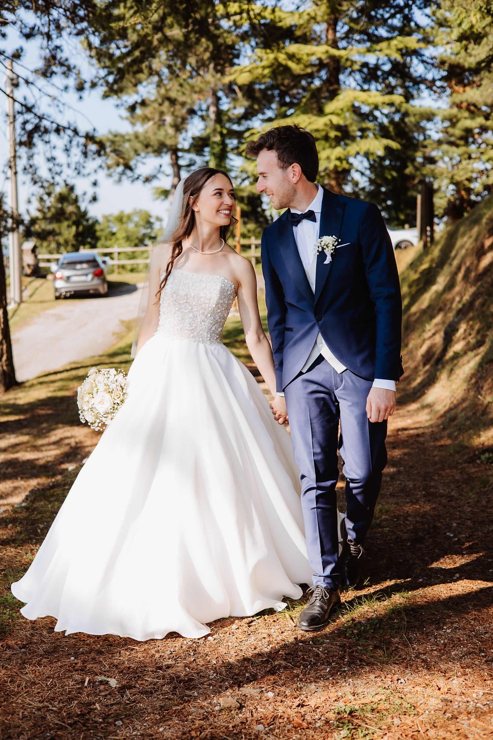 A series of wedding photos showing a couple in formal attire walking among tall pine trees on an outdoor forest path.