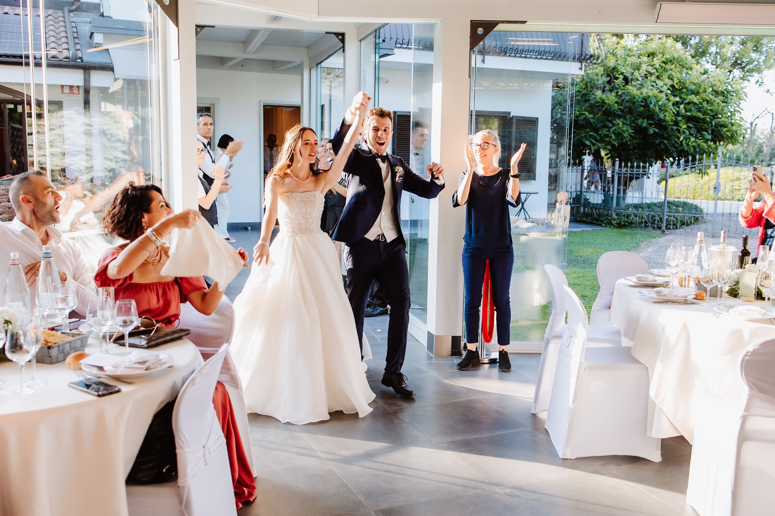 Wedding guests dancing together in an elegant white reception venue during a celebration.