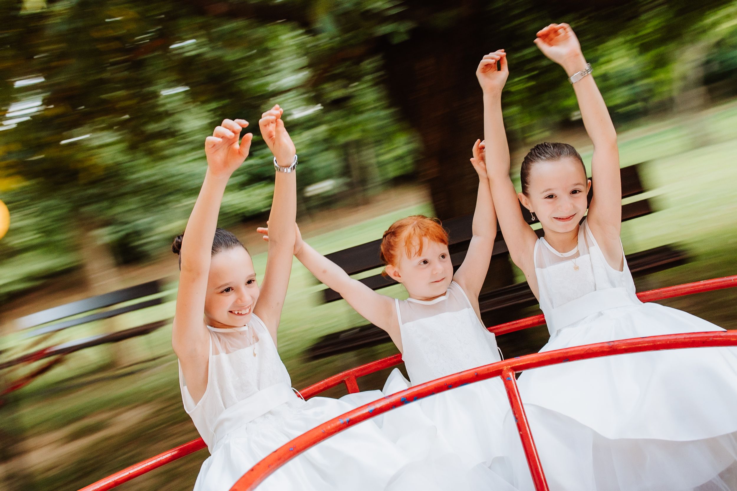 A sequence of motion-blurred photos shows children riding a merry-go-round in white outfits with a red rim.