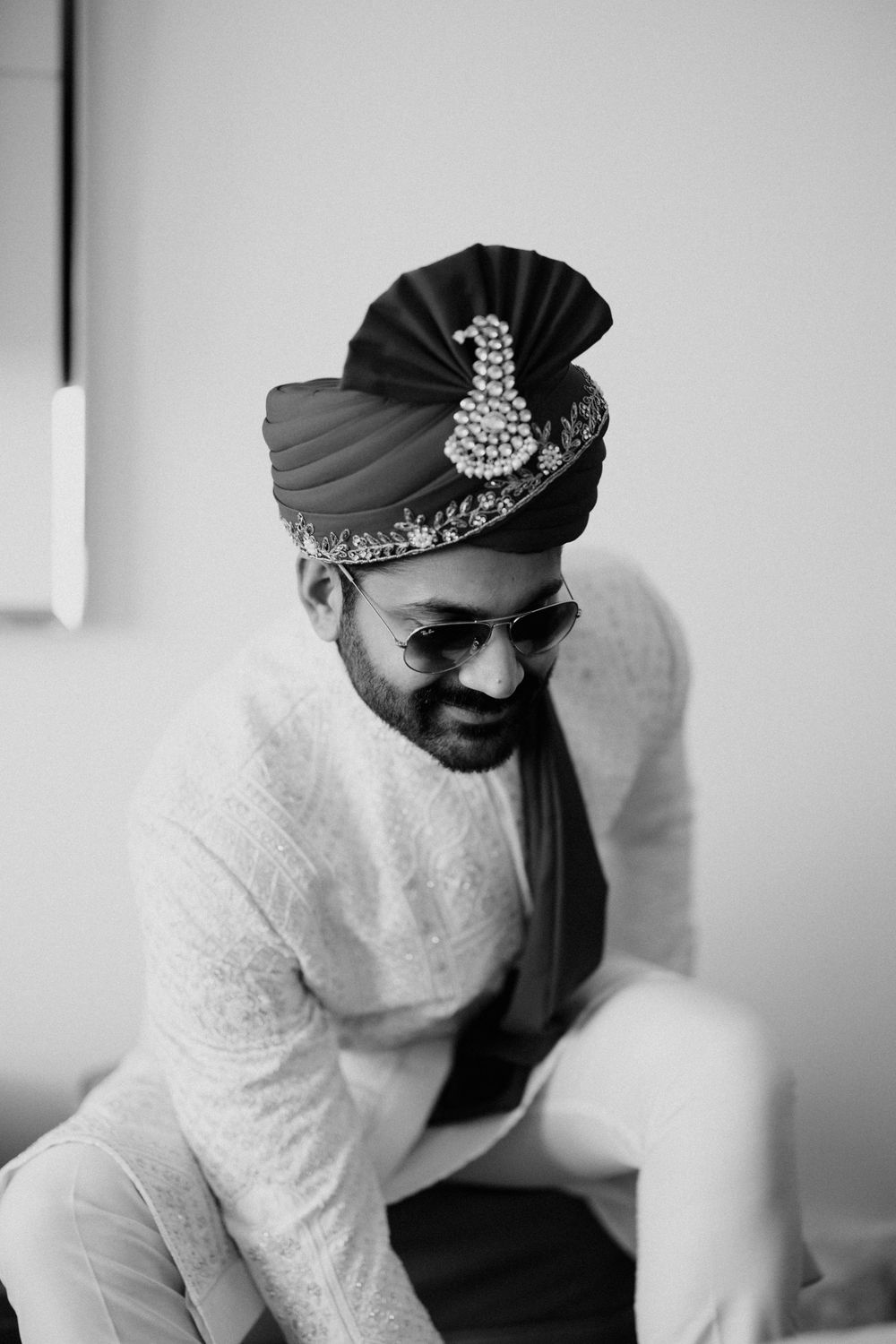 Black and white photo of a person in traditional wedding attire adjusting their headpiece.