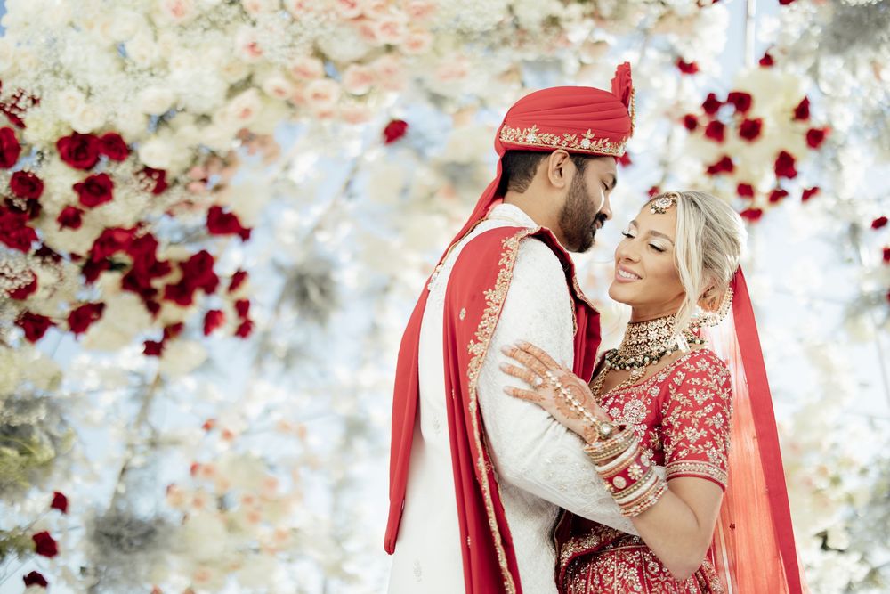 Wedding celebration with red rose petals flying through the air during a joyous moment.