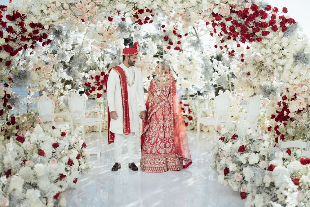 Luxurious wedding backdrop with white and red floral wall arrangements.
