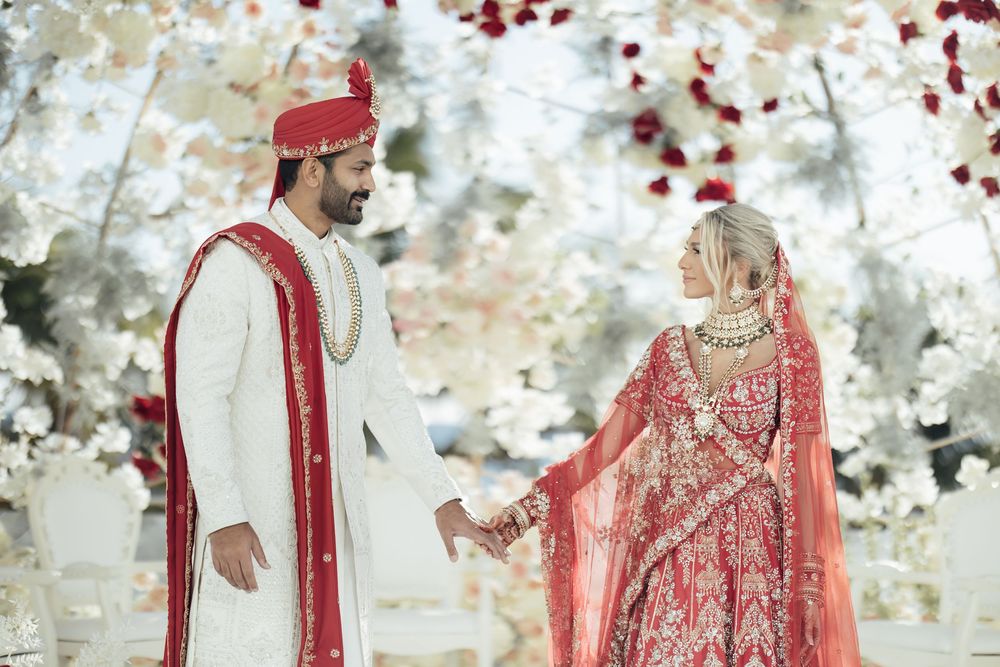 Romantic wedding portrait session with couple in traditional Indian wedding attire against light background.