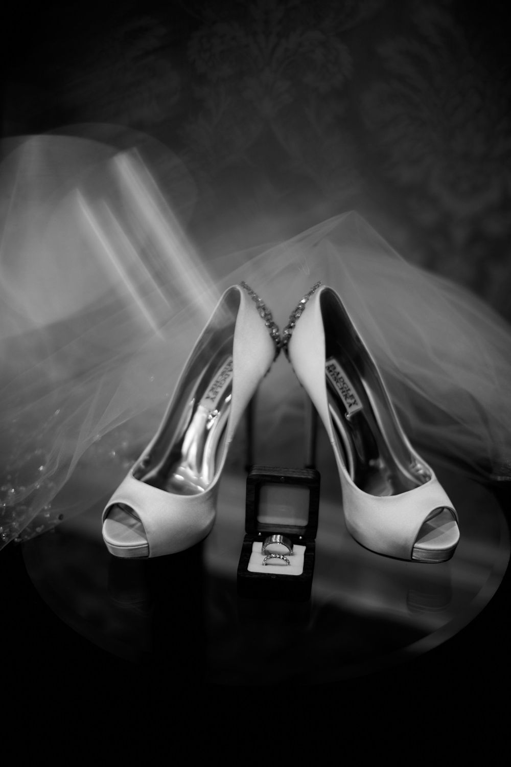 A black and white photo of elegant white bridal heels and perfume bottle arranged with flowing tulle veil. at VIVO RESTAURANT