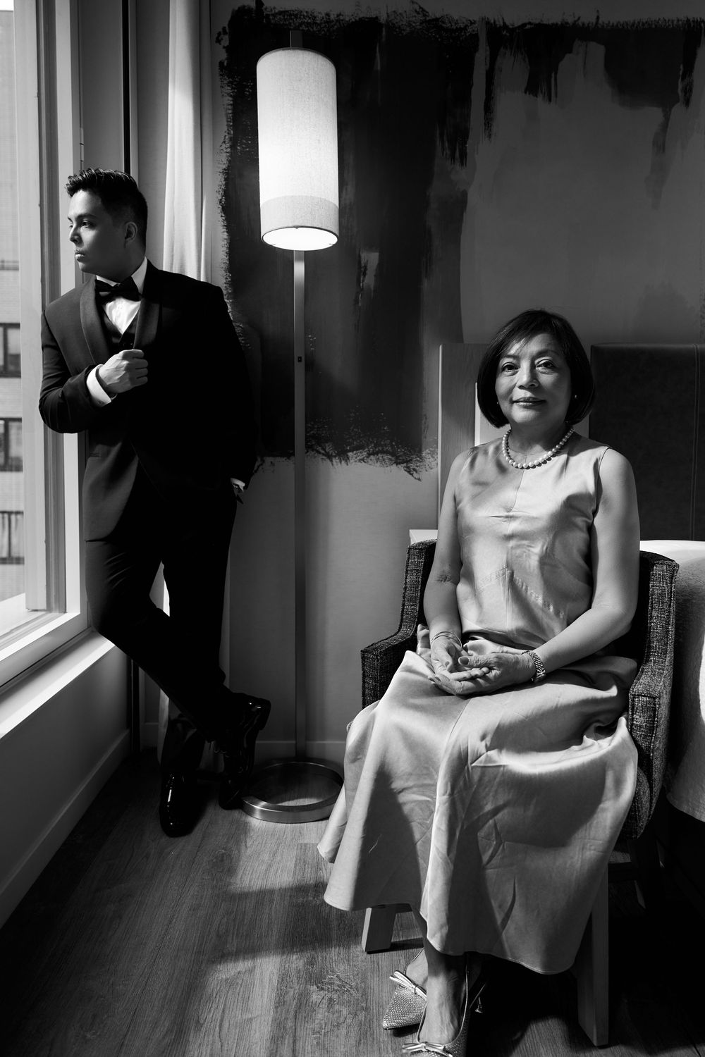 A black and white photo series of a person in a light dress sitting near windows in different moody poses.Hilton club the central 5th