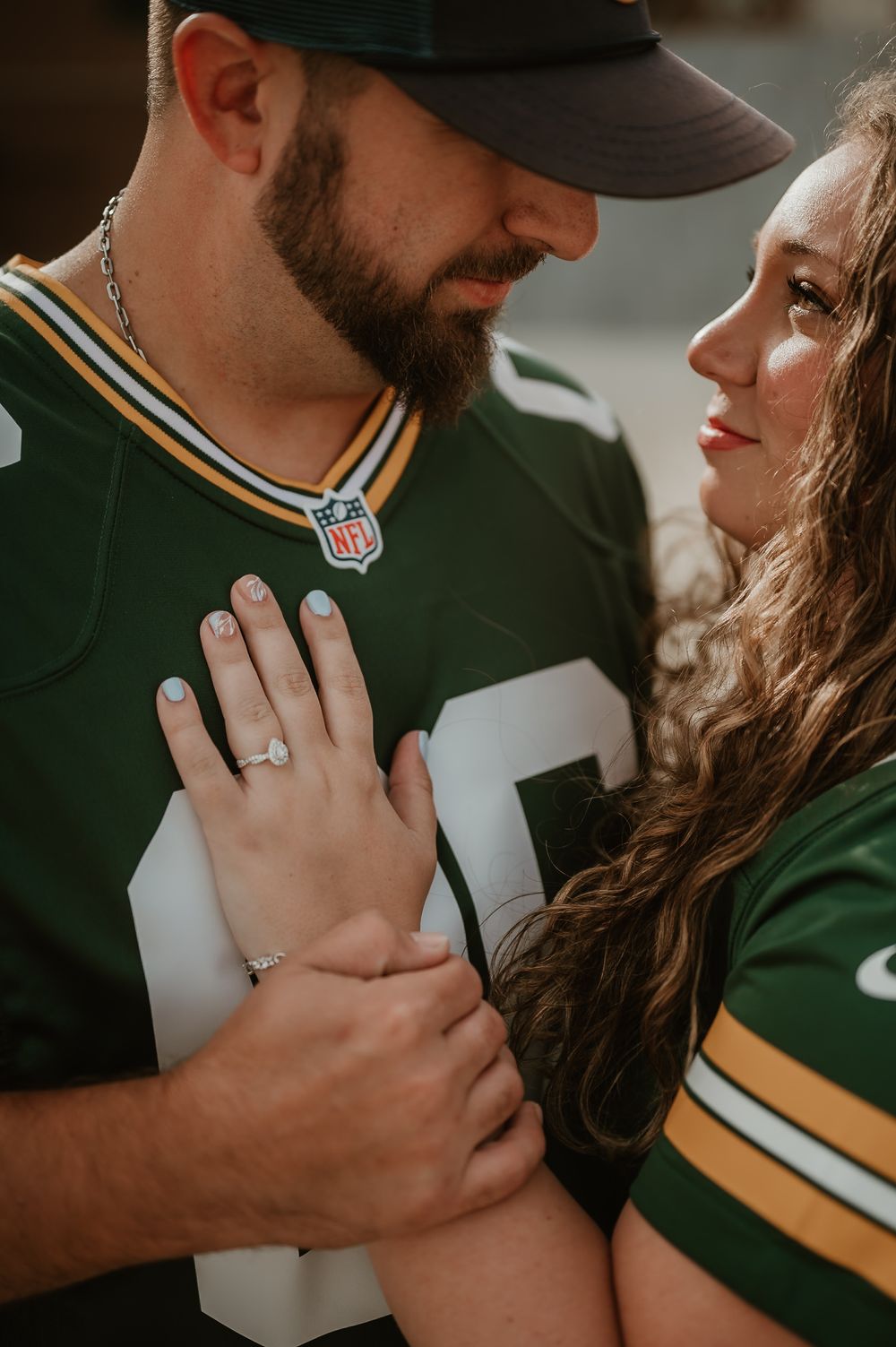 Close-up detail shots of a couple in Green Bay Packers NFL jerseys showing engagement ring and intimate moments.