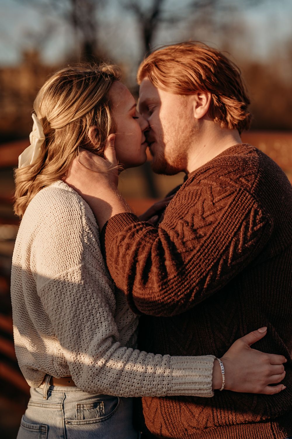A couple in warm knit sweaters sharing tender moments during a sunset photoshoot.