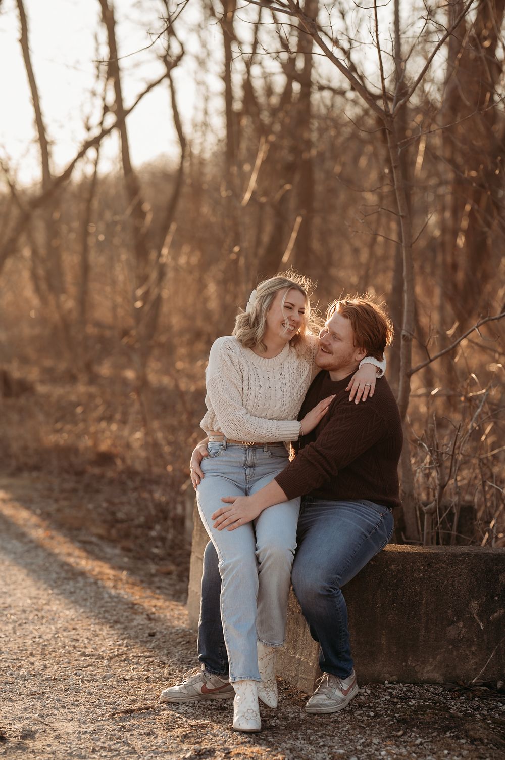 Couple sharing affectionate moments on a woodland path during golden hour sunset.
