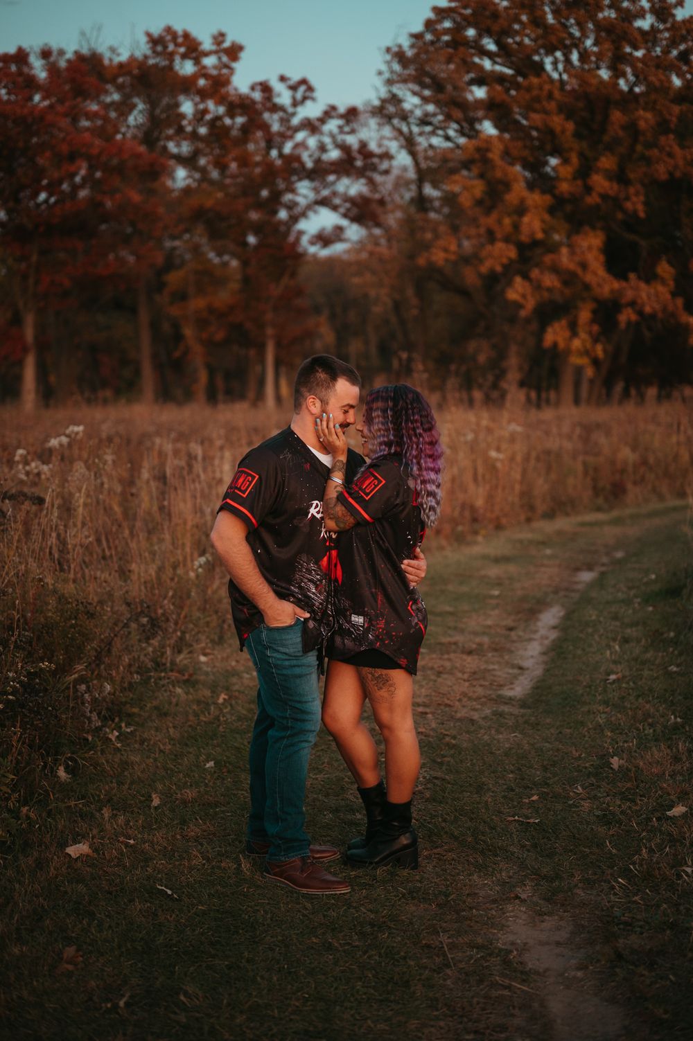 A romantic autumn photo shoot on a rustic path surrounded by warm fall foliage at sunset.