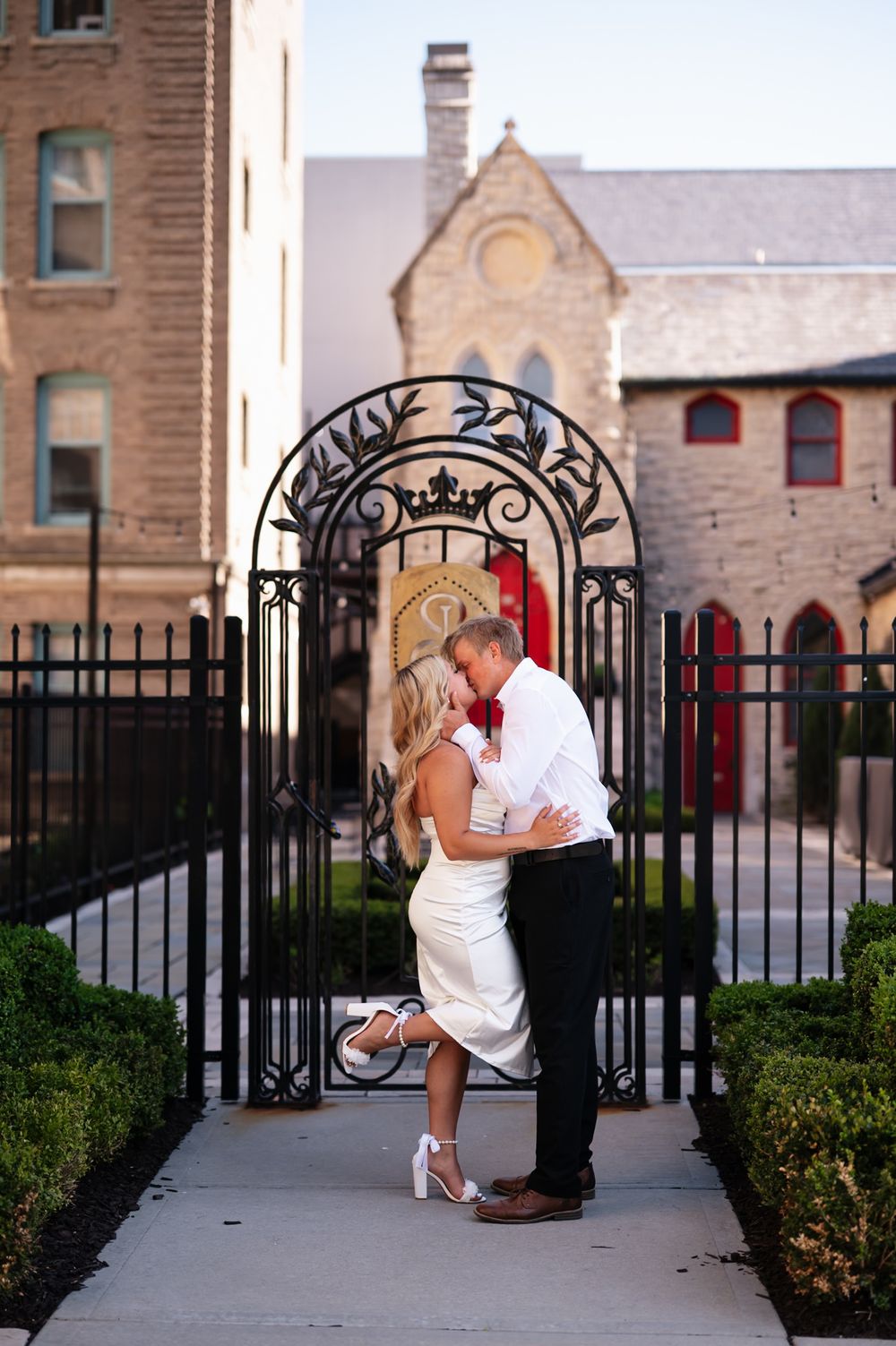 Four sequential photos showing a romantic outdoor proposal scene through decorative metal gates at a church courtyard.