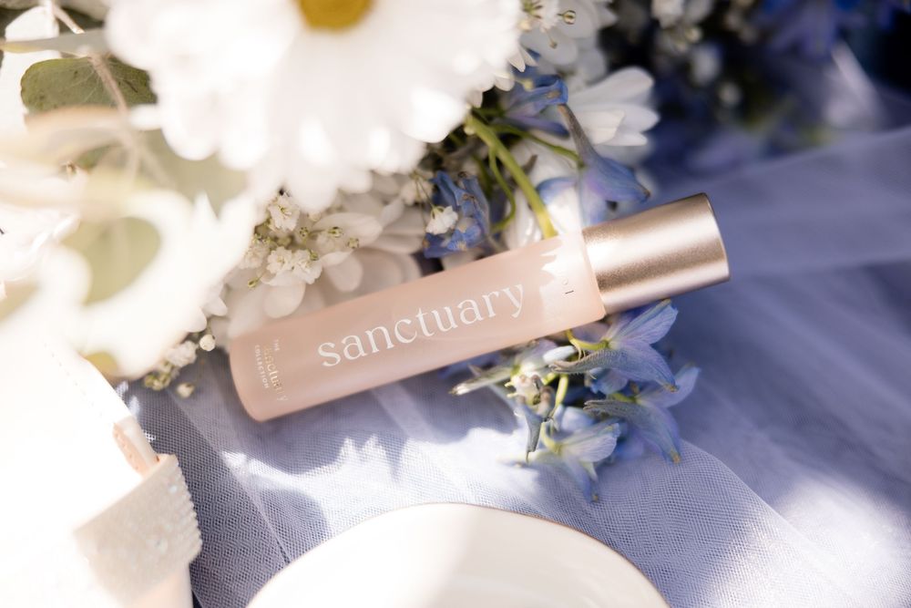 A person showing pink lipstick and lipgloss product swatches on their arm against a glittery background.