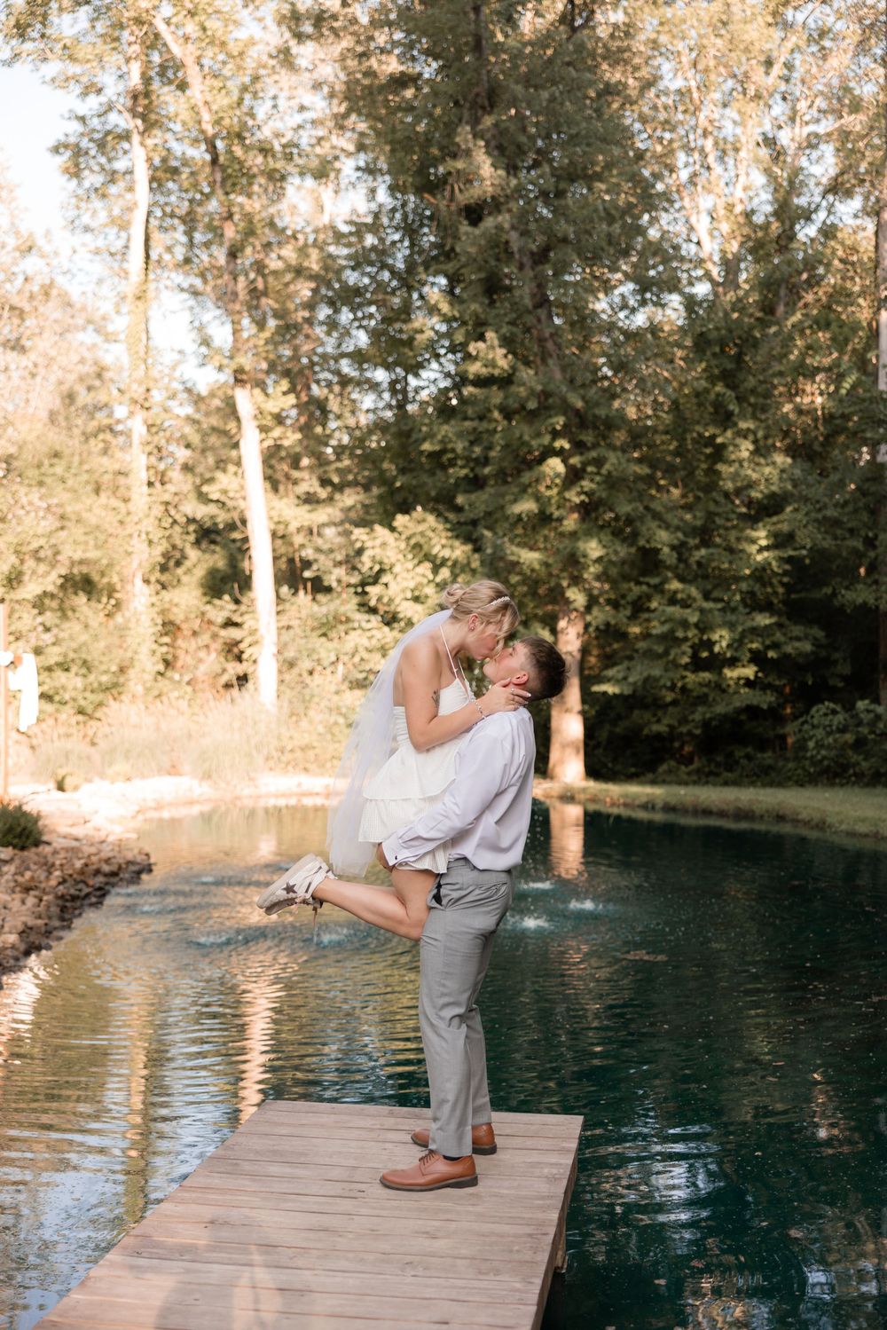 Romantic couple shares intimate moments on a wooden dock by a serene pond during golden hour.