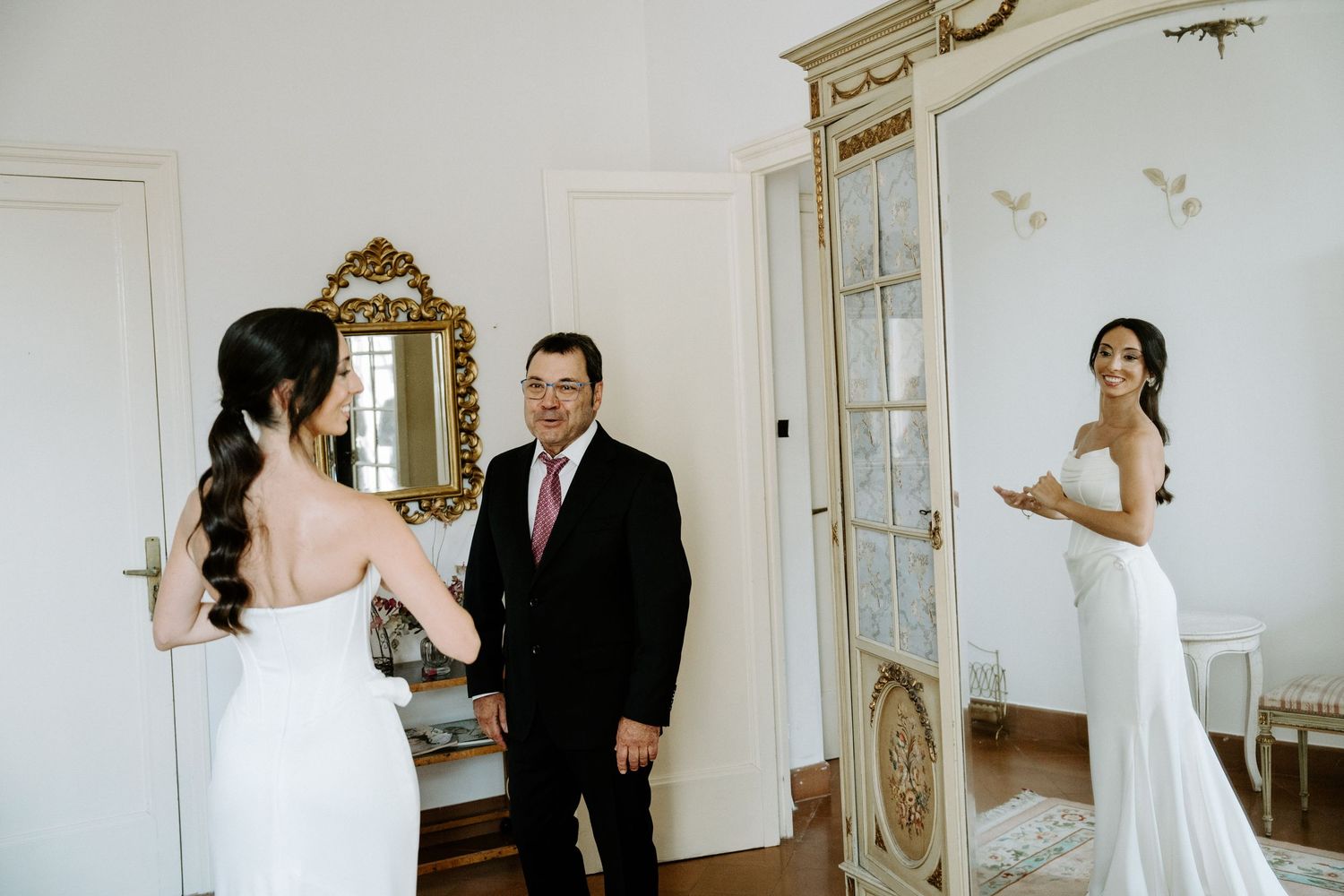 A series of intimate first look moments between a bride and groom in an elegant white room with ornate mirrors.