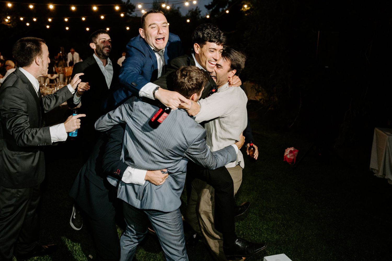 Evening wedding reception with string lights and dancing guests creating a festive atmosphere.