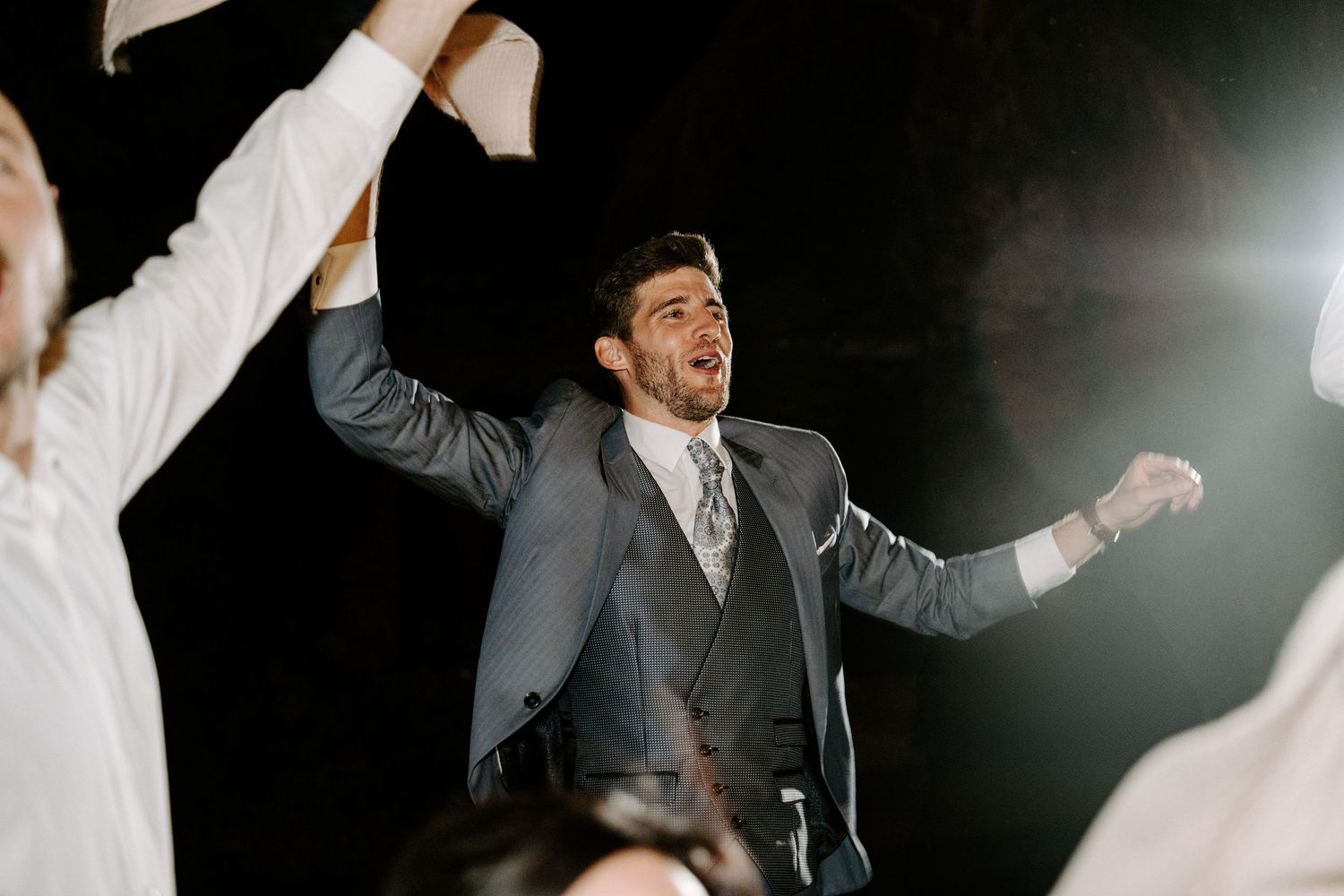 Guests dancing and celebrating at a nighttime wedding reception with dramatic lighting.