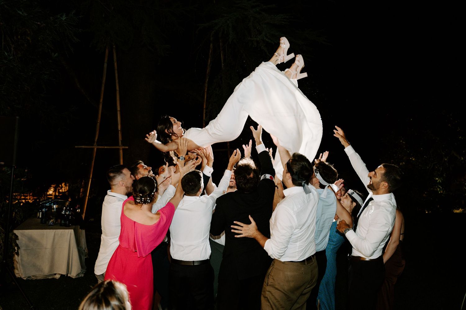 Wedding reception guests dancing together under dark evening skies.