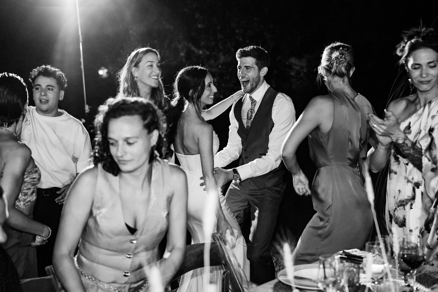 Wedding guests dancing and celebrating during an evening reception party.