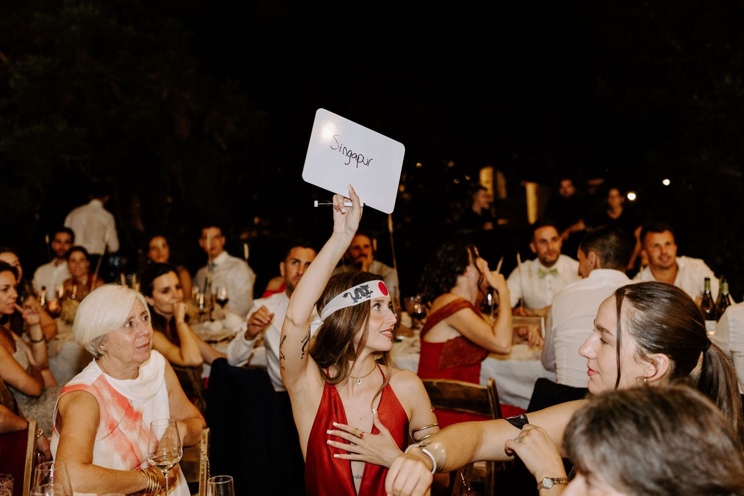 Excited wedding guests celebrating and holding up signs during an outdoor reception.