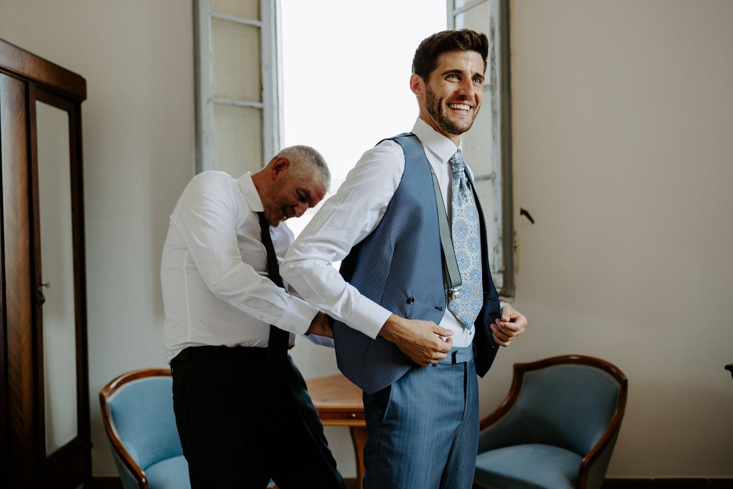 Wedding party members sharing joyful reactions in a light-filled indoor space.