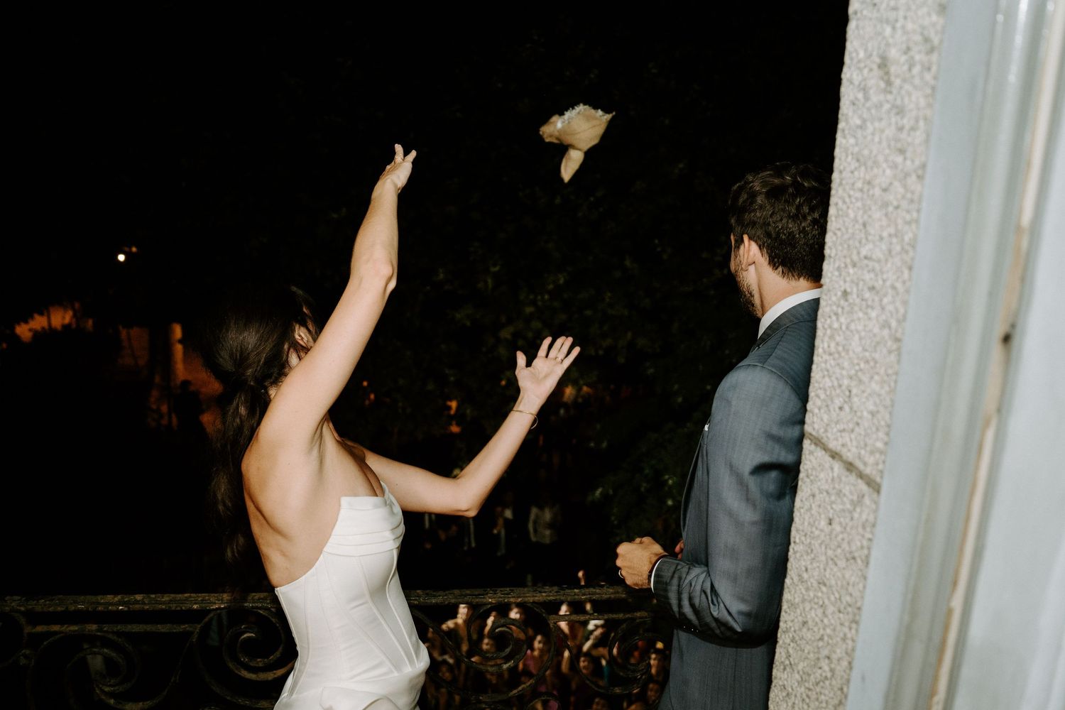 A bride in a white dress holds up a sports jersey at a wedding reception celebration.