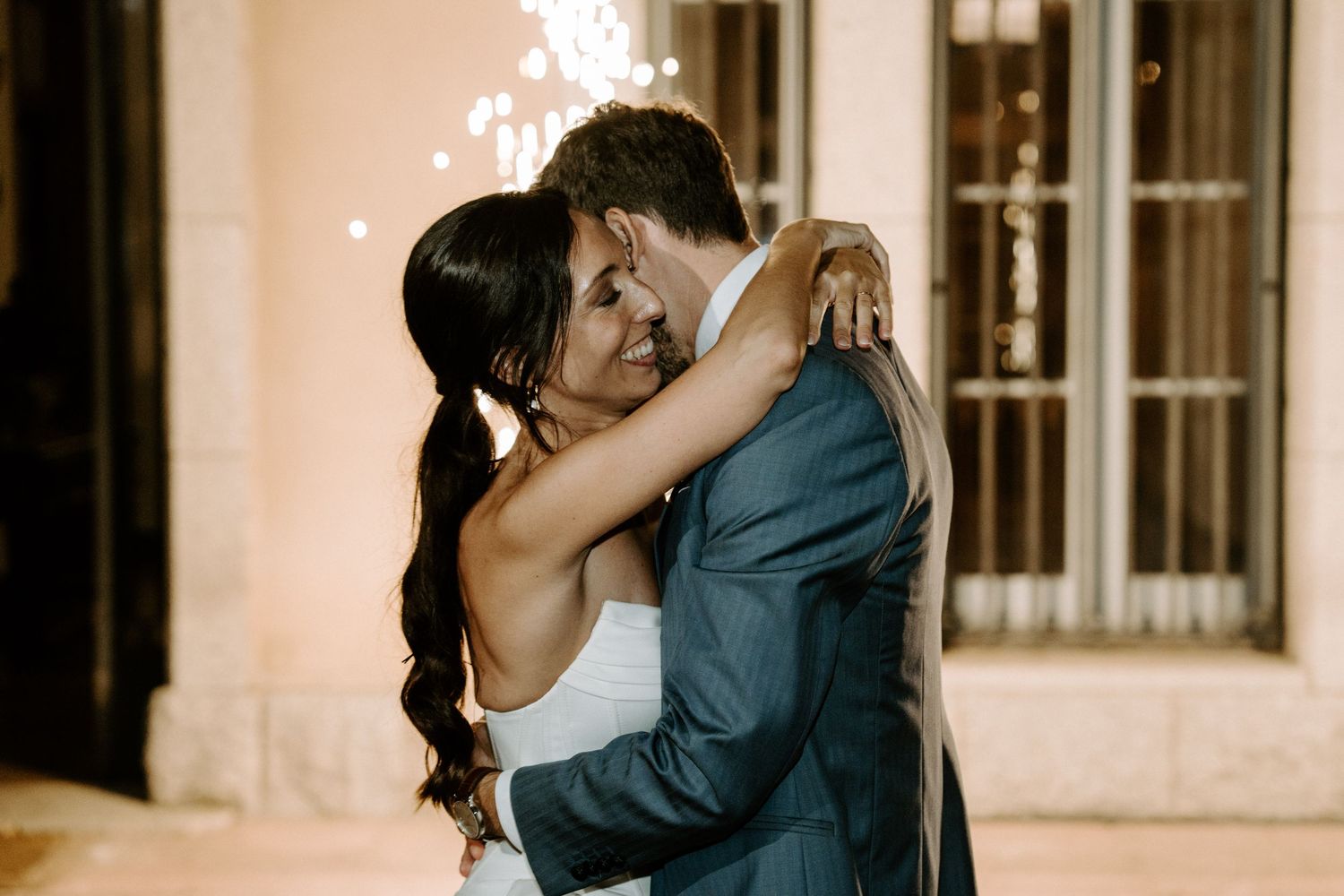 Wedding guests dance and celebrate in a dimly lit reception hall.