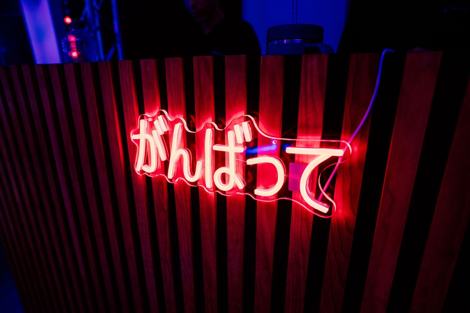 Neon signs illuminate a dark venue space with blue and red lighting.