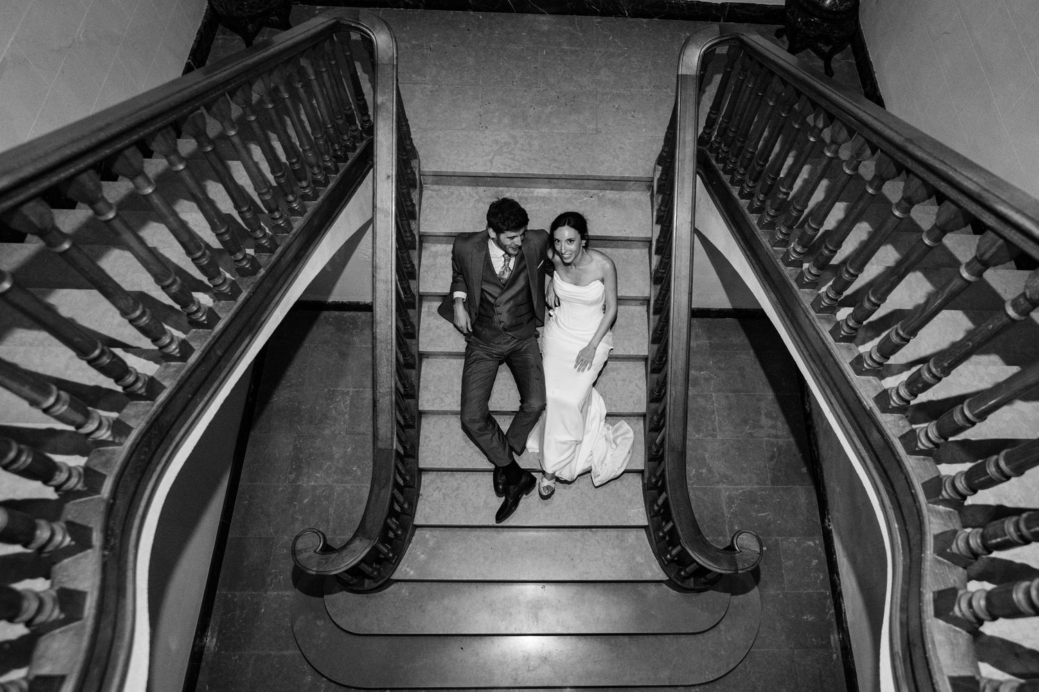 Black and white view of an elegant staircase with ornate banisters and architectural details.
