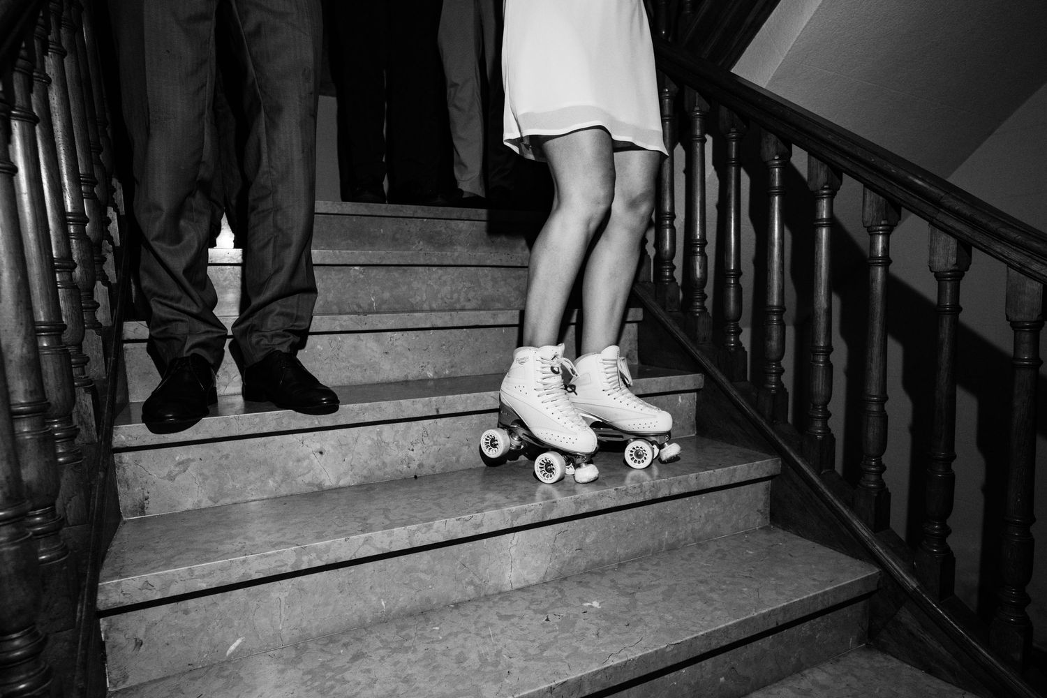 Black and white photo of people's feet and legs on vintage wooden stairs.