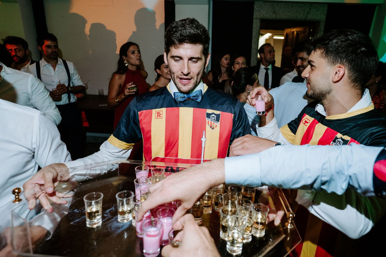 Partygoers celebrating with red and yellow striped flags at an indoor event.