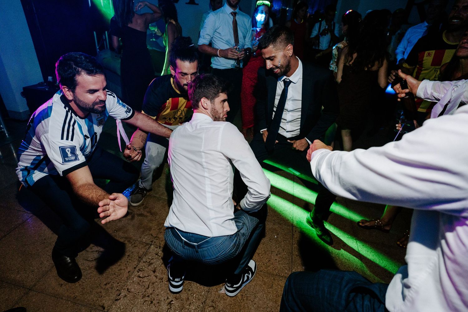 Nightclub scene with green lighting and people dancing on a dark dance floor.