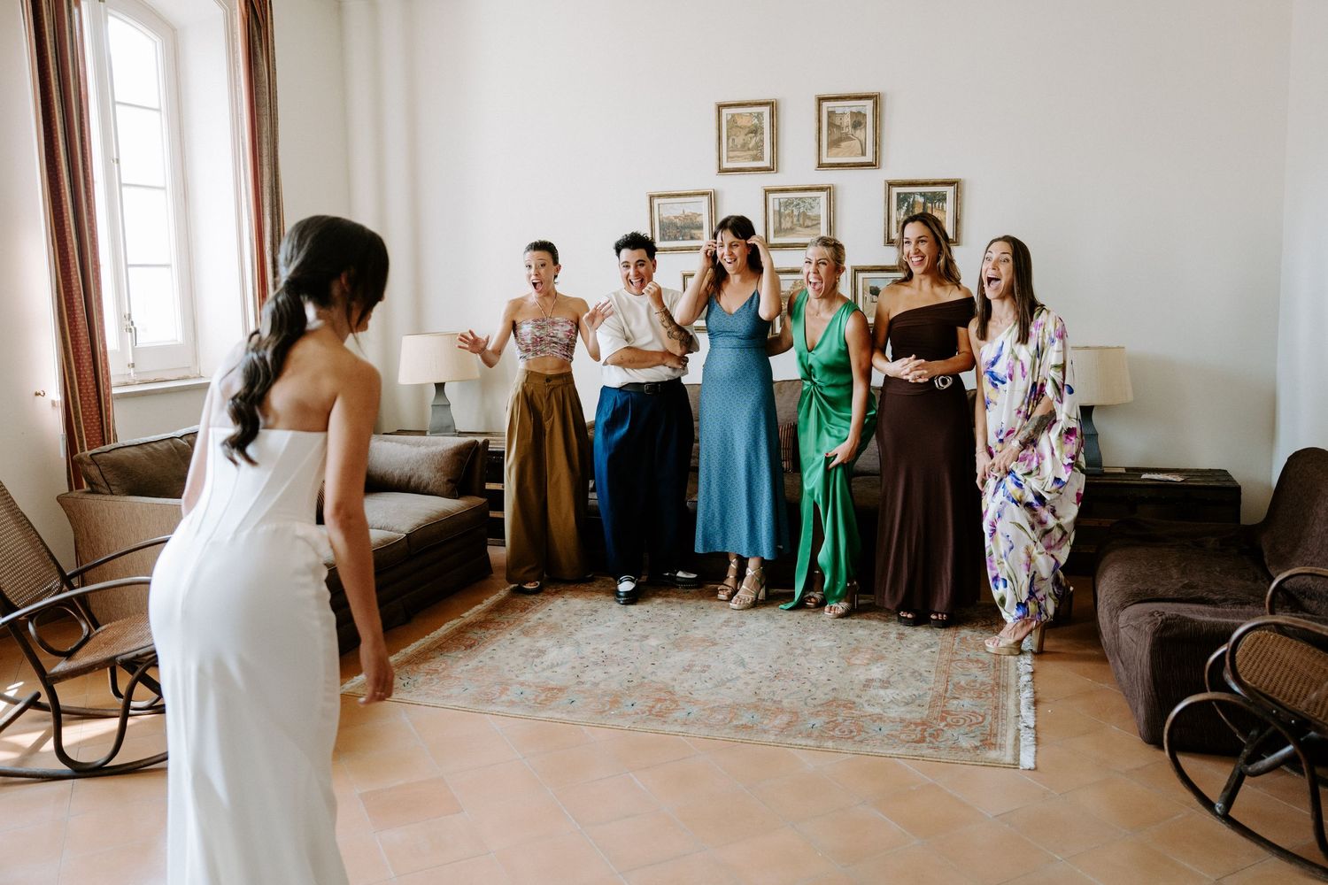 Wedding guests seated in rows watching a ceremony in an elegant white room.