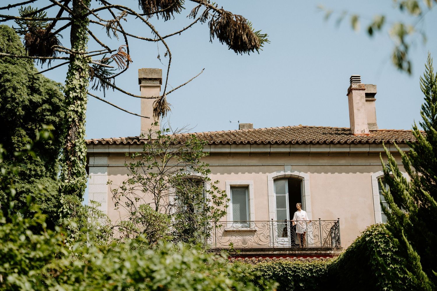 Mediterranean-style villa with pink walls and traditional roof tiles against blue sky.