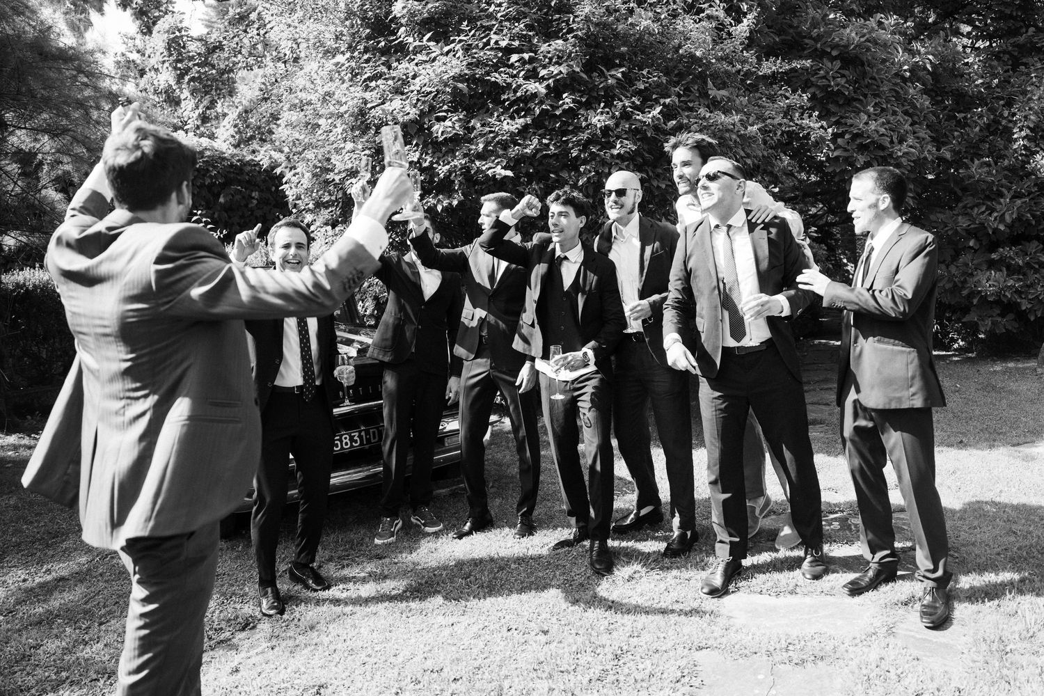 A black and white photo of a wedding party posing playfully outdoors.