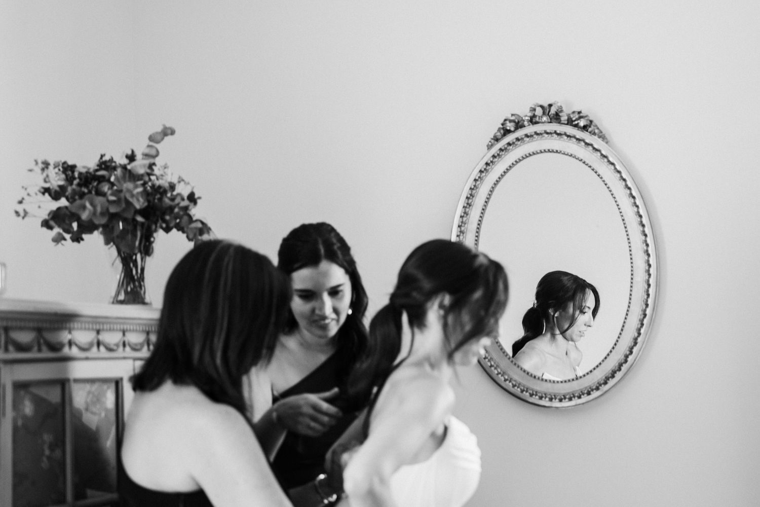 Black and white photo of a group gathered around an ornate mirror.