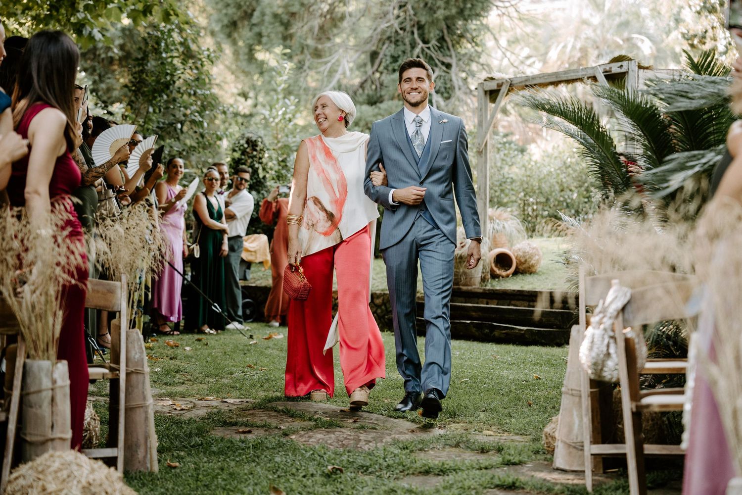Wedding ceremony processional on an outdoor path lined with decorative elements.