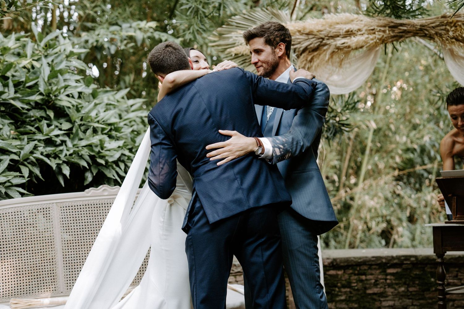 Emotional embraces shared during wedding ceremony in a lush garden setting.
