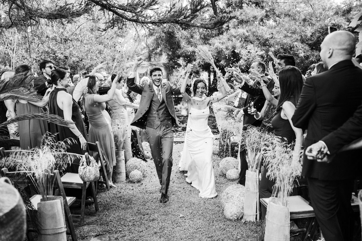 Wedding guests celebrating with confetti toss in black and white photography.