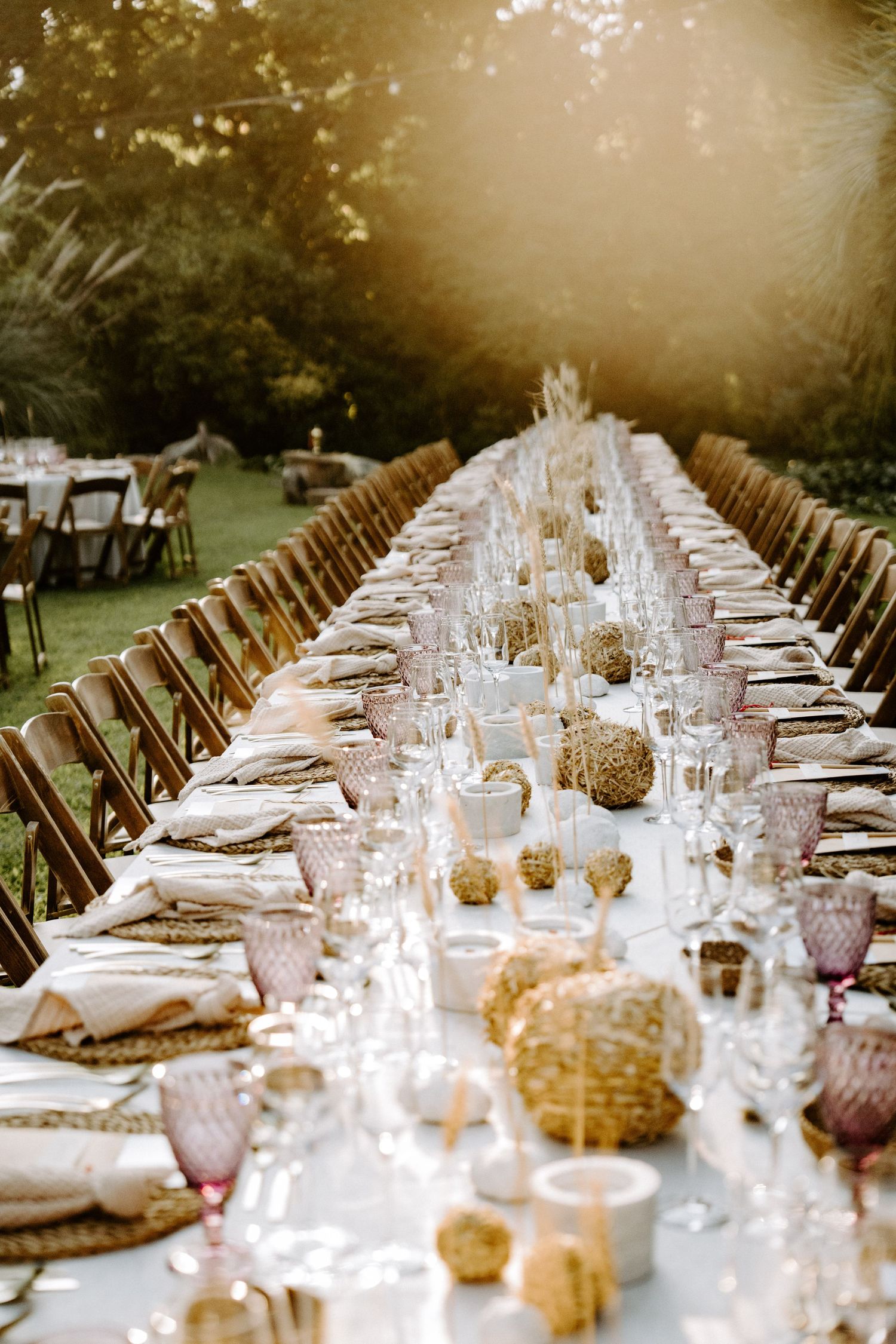 Elegant long table wedding reception setup with crystal glassware and golden accents.
