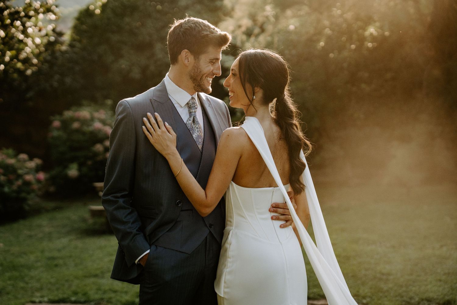 Romantic sunset portrait of newlyweds embracing in a garden setting. Jardins el Roquer