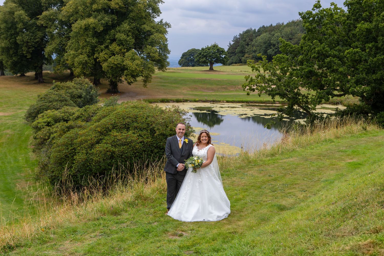 Rolling green hills and trees provide scenic backdrop for outdoor wedding photography.