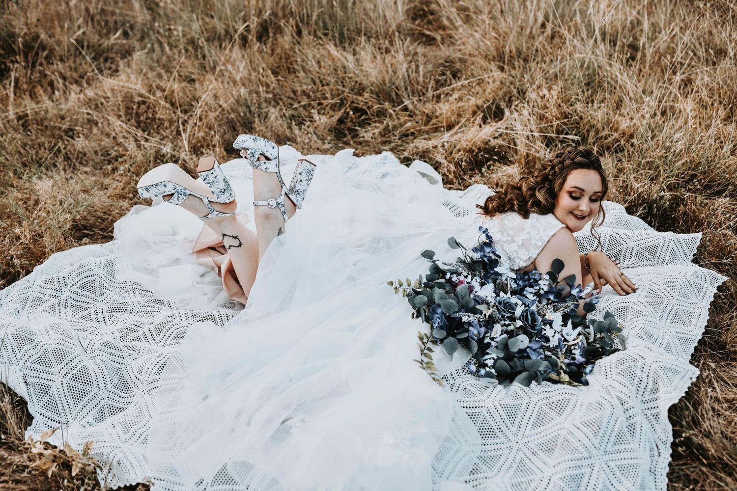 Bride with curly hair and braid wearing embroidered veil in golden Corinth, Texas landscape.