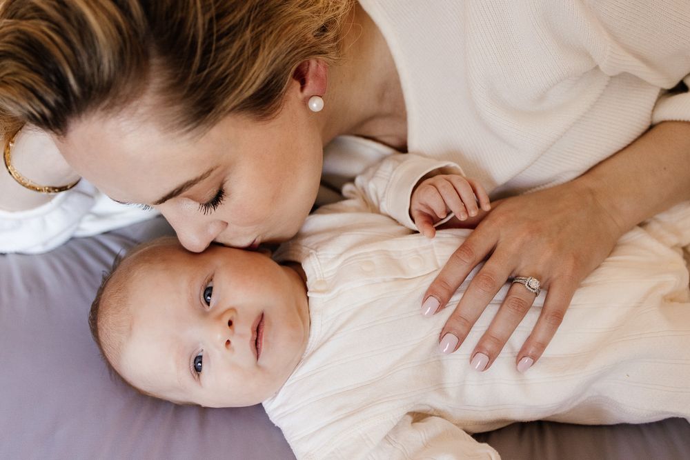 Mother kisses her baby's cheek during an in-home Bay Area newborn photoshoot in Los Altos Hills