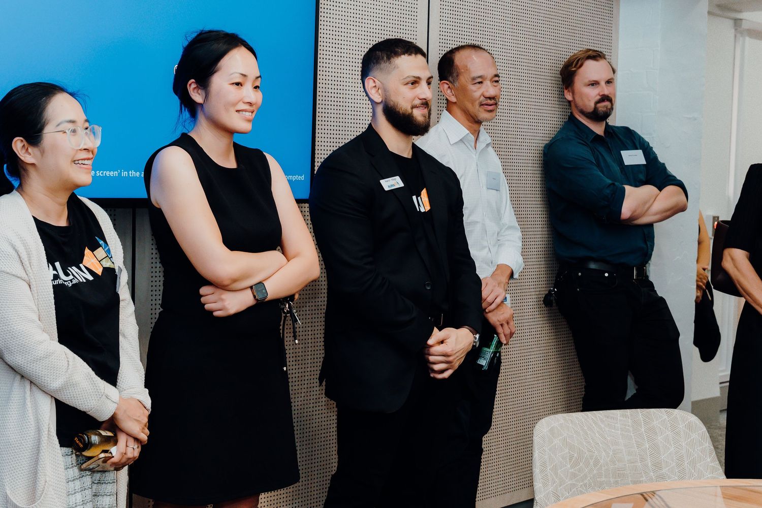 A diverse group of professionals standing in a line against a wall at a business meeting or workshop.