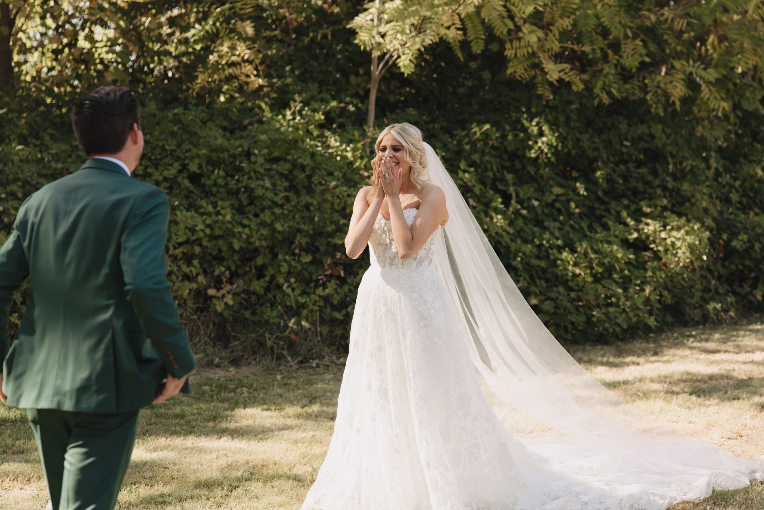 A couple shares a private moment among trees during an outdoor wedding photo session in forest surroundings.