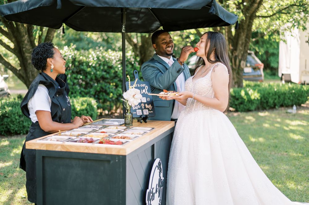 Catering staff serves appetizers and beverages at an outdoor event with trees in the background.