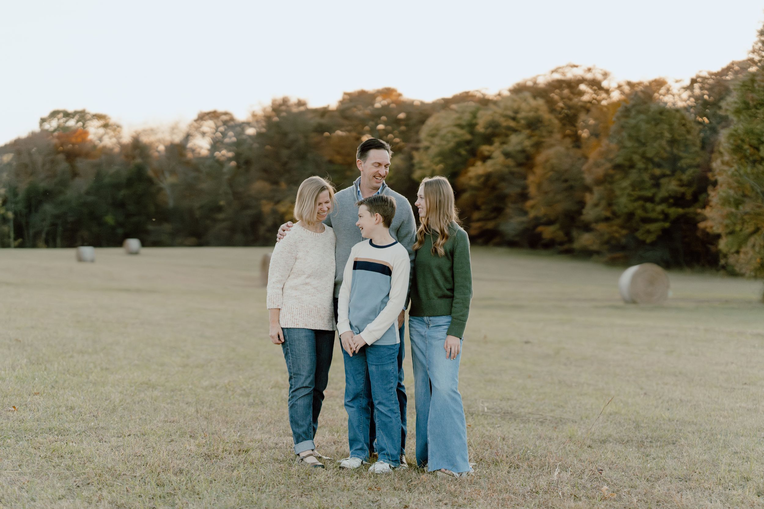 A small group stands together in a golden autumn field at sunset.