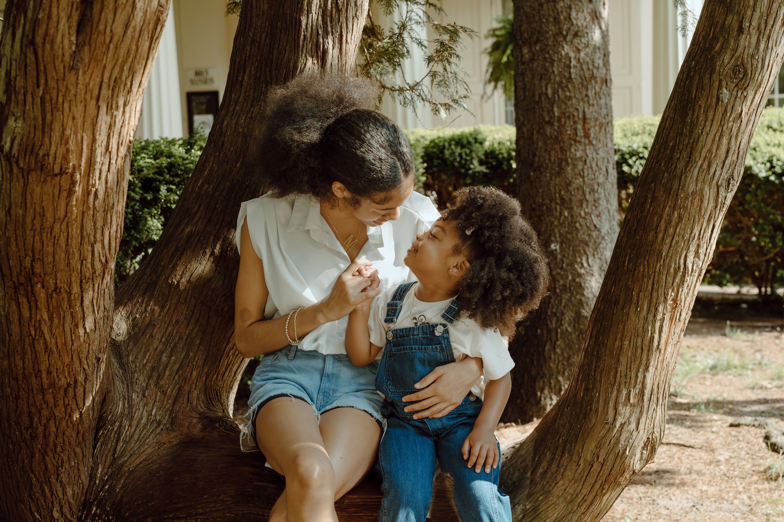 A tender moment of play between parent and child sitting on a tree trunk.