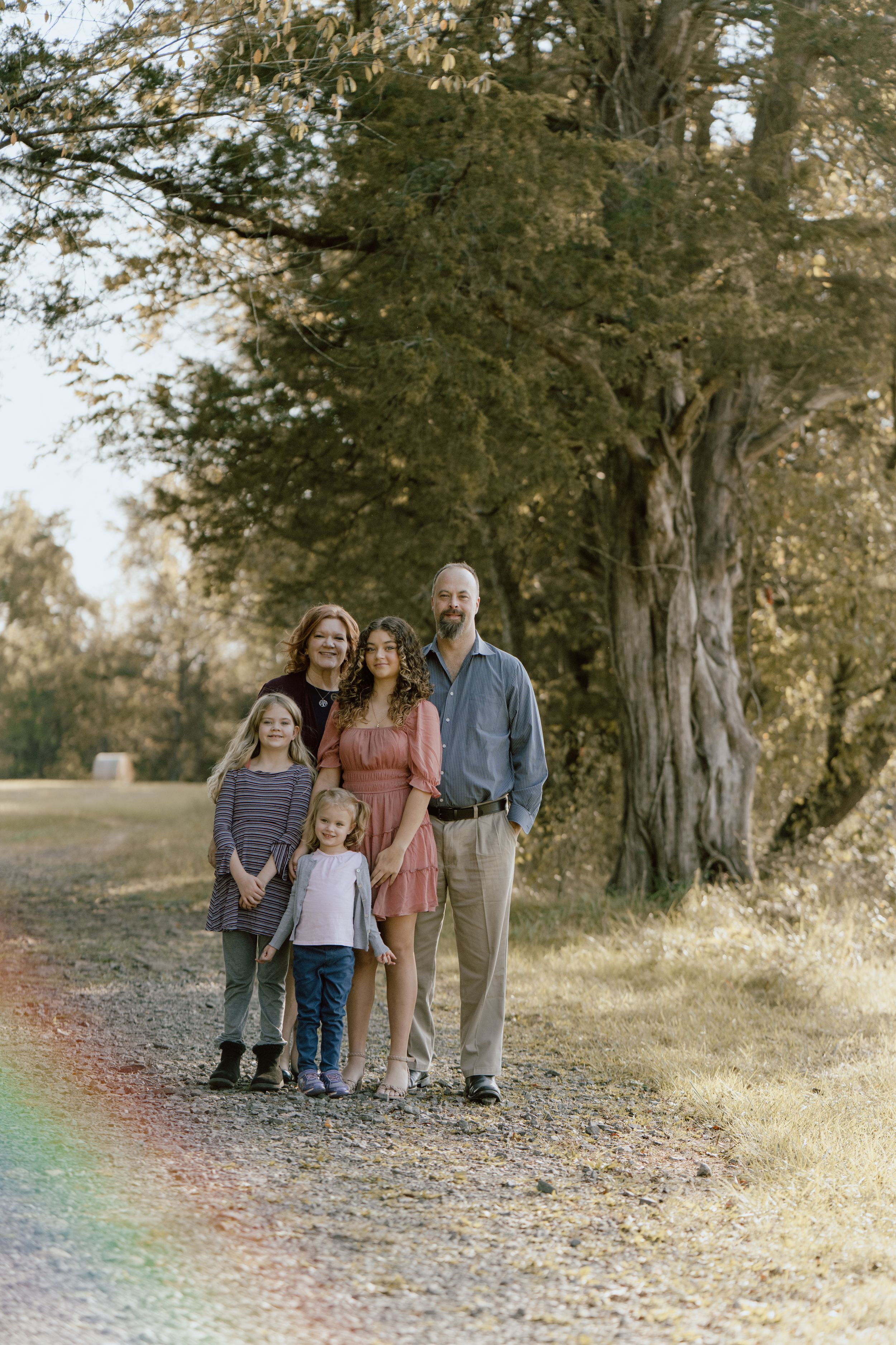 Family posing together on a nature path with fall foliage in the background.