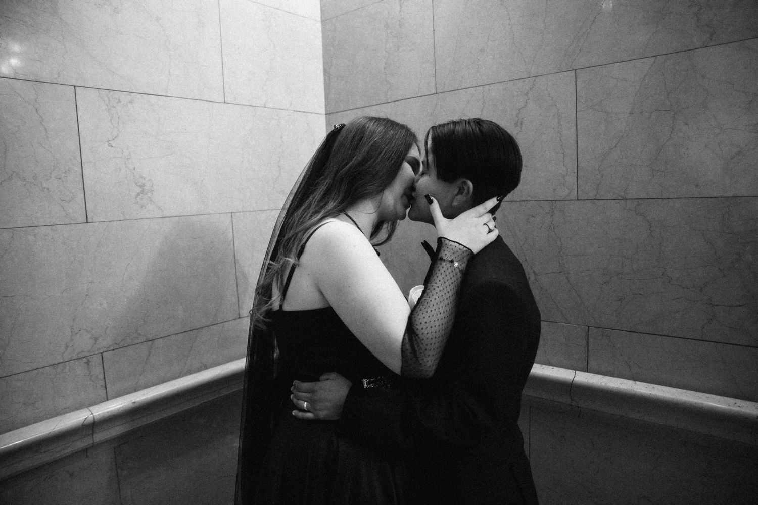 A romantic black and white photo of a couple in formal attire sharing an intimate moment.